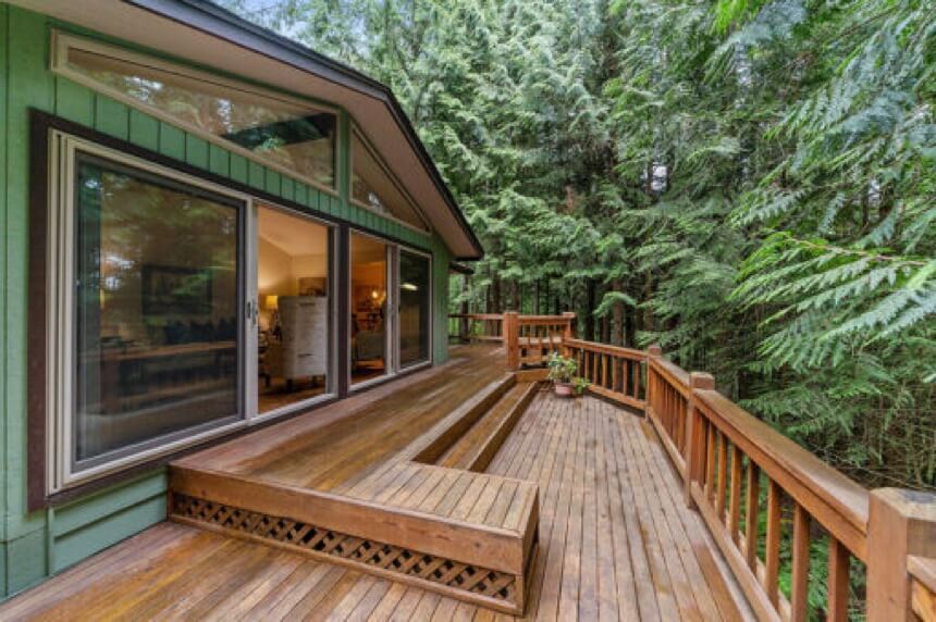 Stained by HPI, multi-level deck off a green mid-century modern house, surrounded by trees