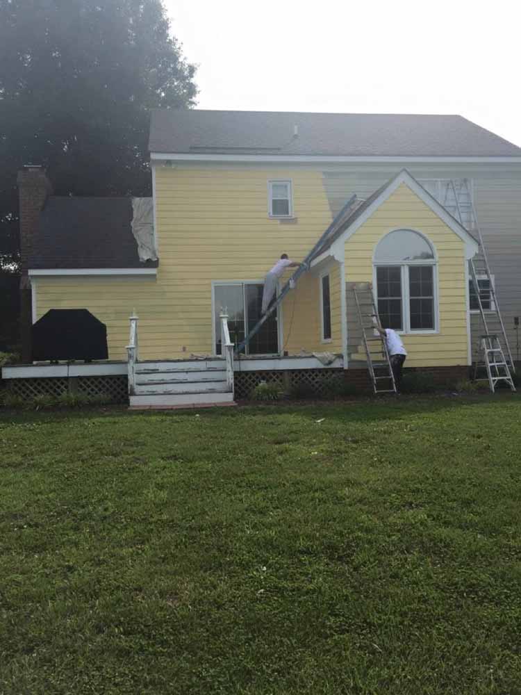 HPI repainting a house from boring beige to cheery yellow
